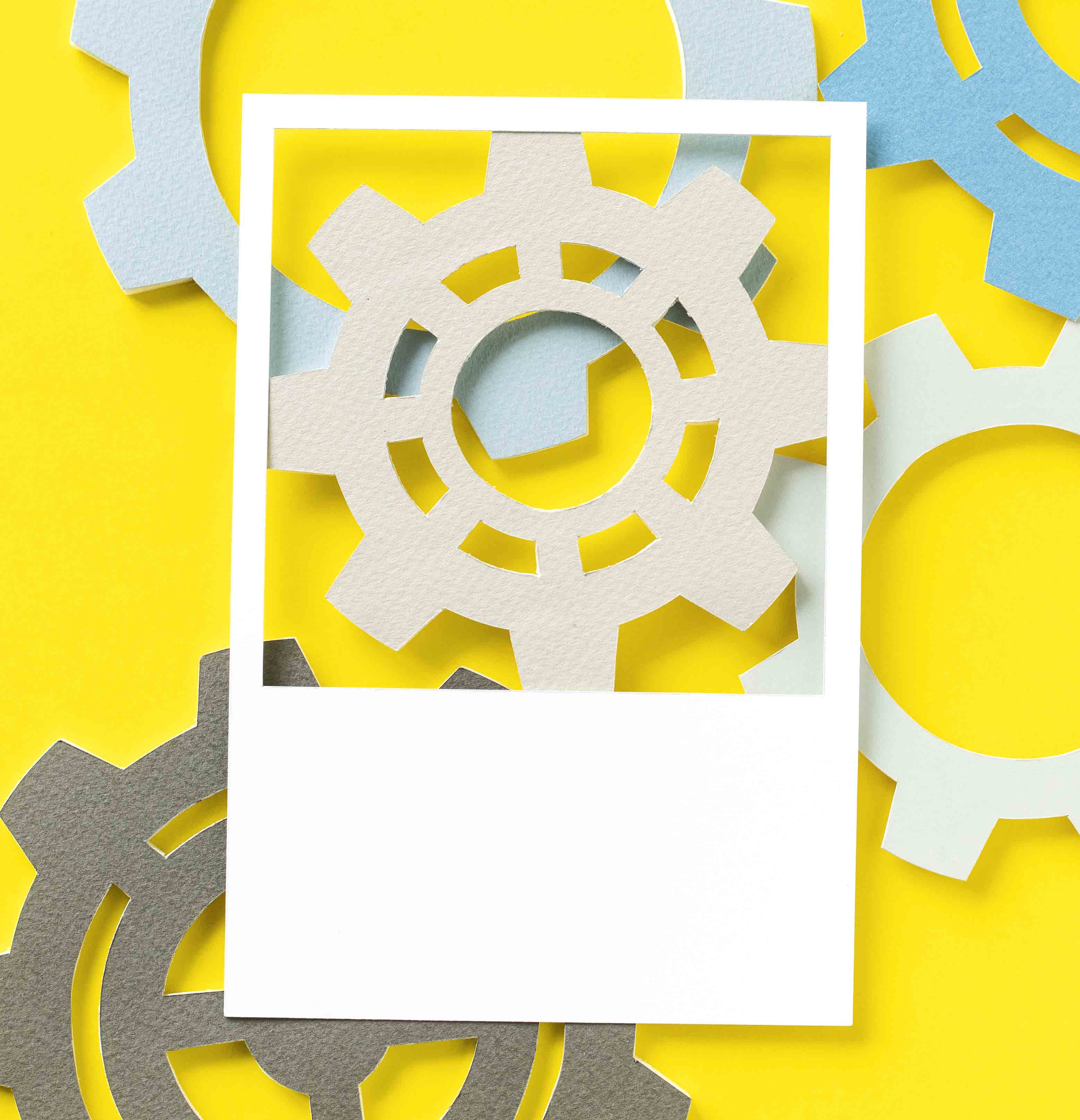 A collection of gears cut out of paper on a yellow background