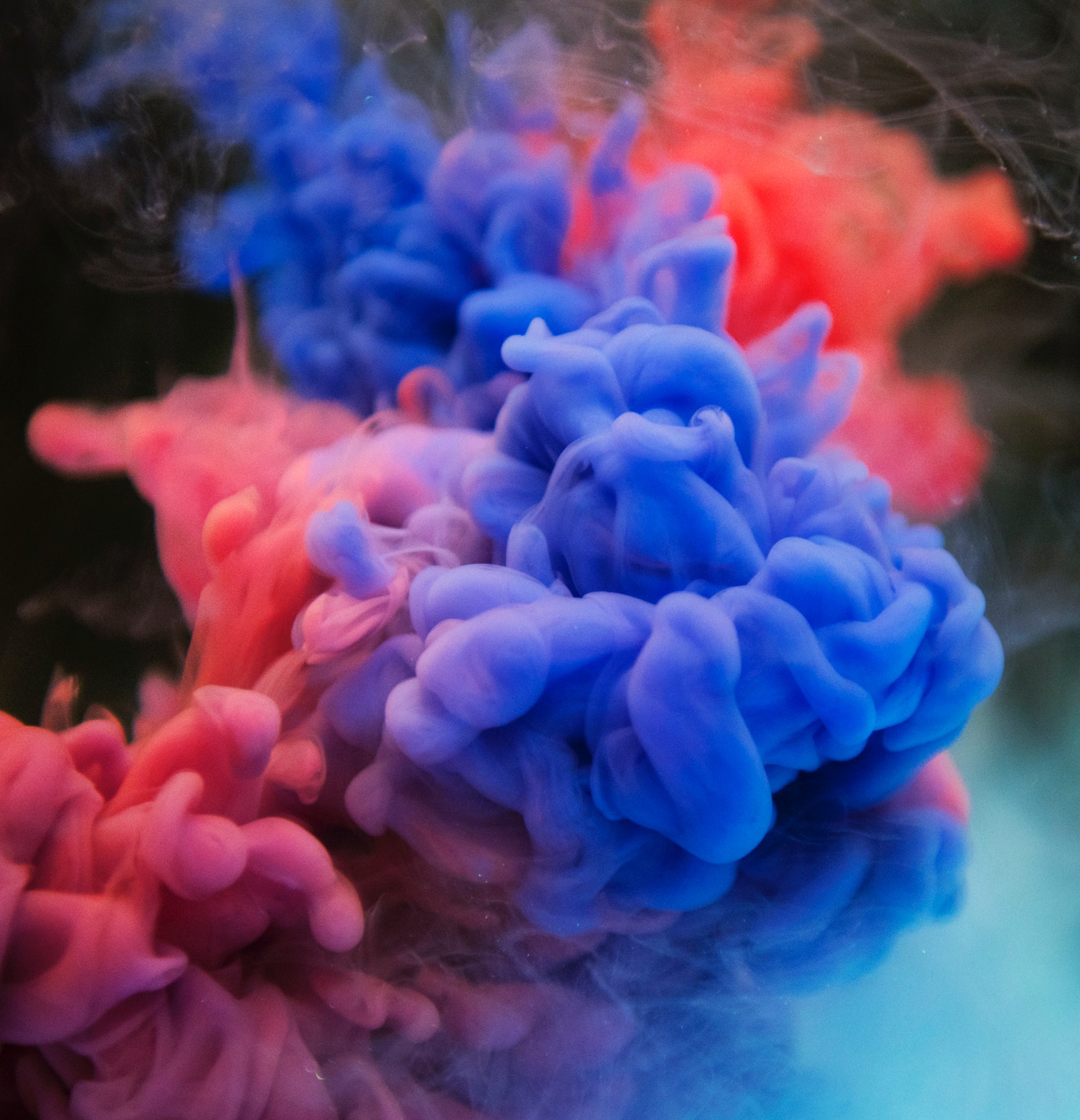 Photograph of swirling pink, blue and red smoke