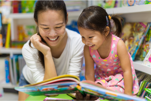 young asian woman and preschooler reading at the library