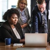 Three people looking at a laptop