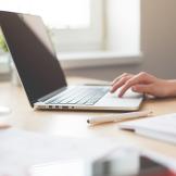 A hand using a touch pad on a laptop computer