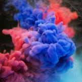 Photograph of swirling pink, blue and red smoke