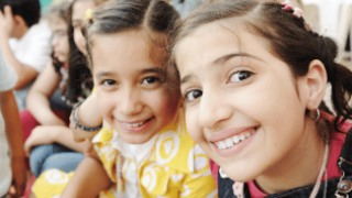 two girls looking happy at the library; close up of their smiling faces